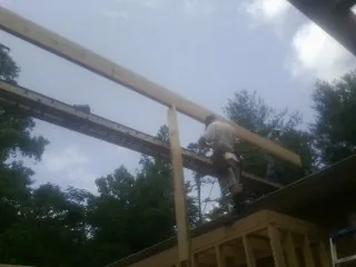 Carpenter setting a ridge beam over a new addition frame — Ice Dam Removal by Roofing Brothers in Barnstable