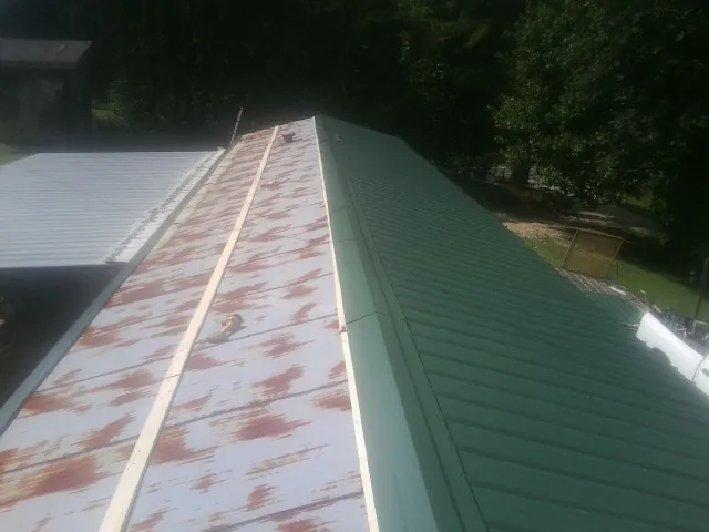 Old rusted panels beside newly installed green metal roofing — Wind Damage Roof Repair by Roofing Brothers in Barnstable