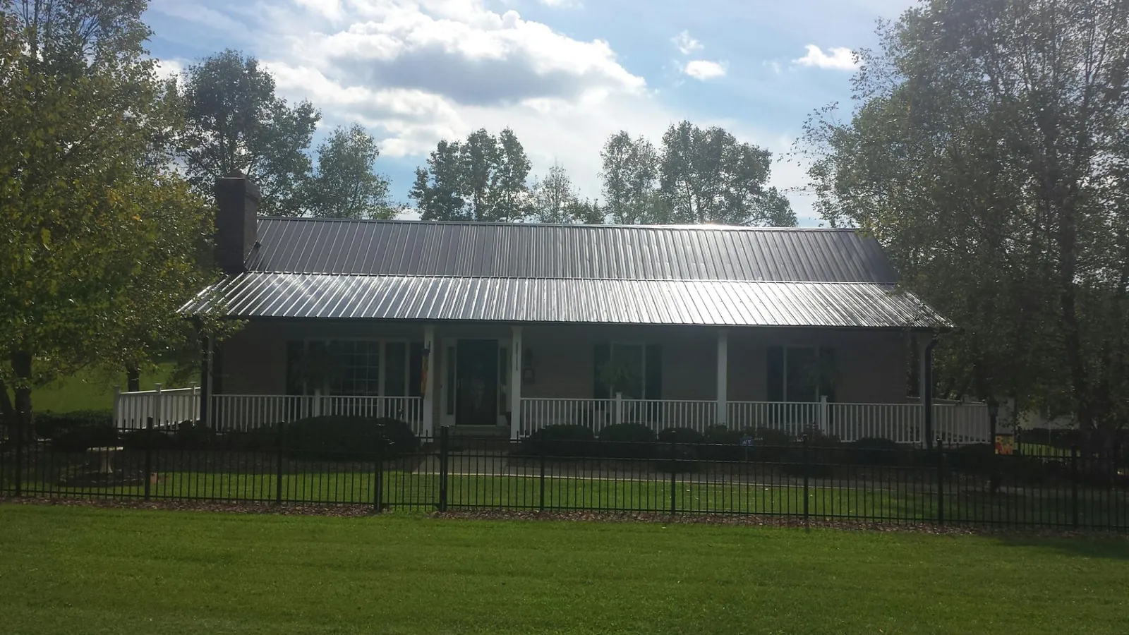 Gray metal roof on a brick ranch with a full width front porch — Gutter Guard Installation work by our crew in Barnstable